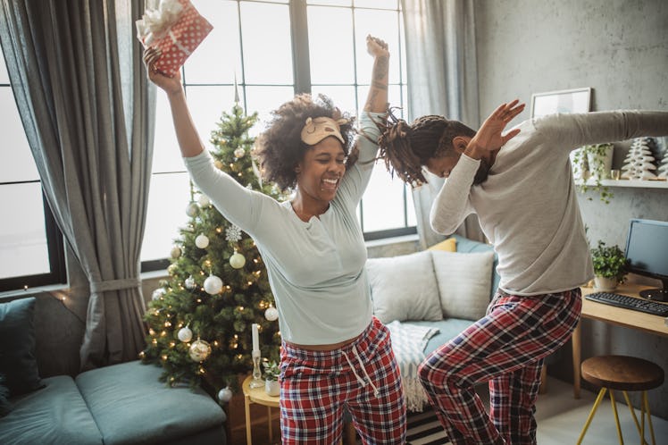 A couple dances around their living room on Christmas morning, wearing matching pajamas.