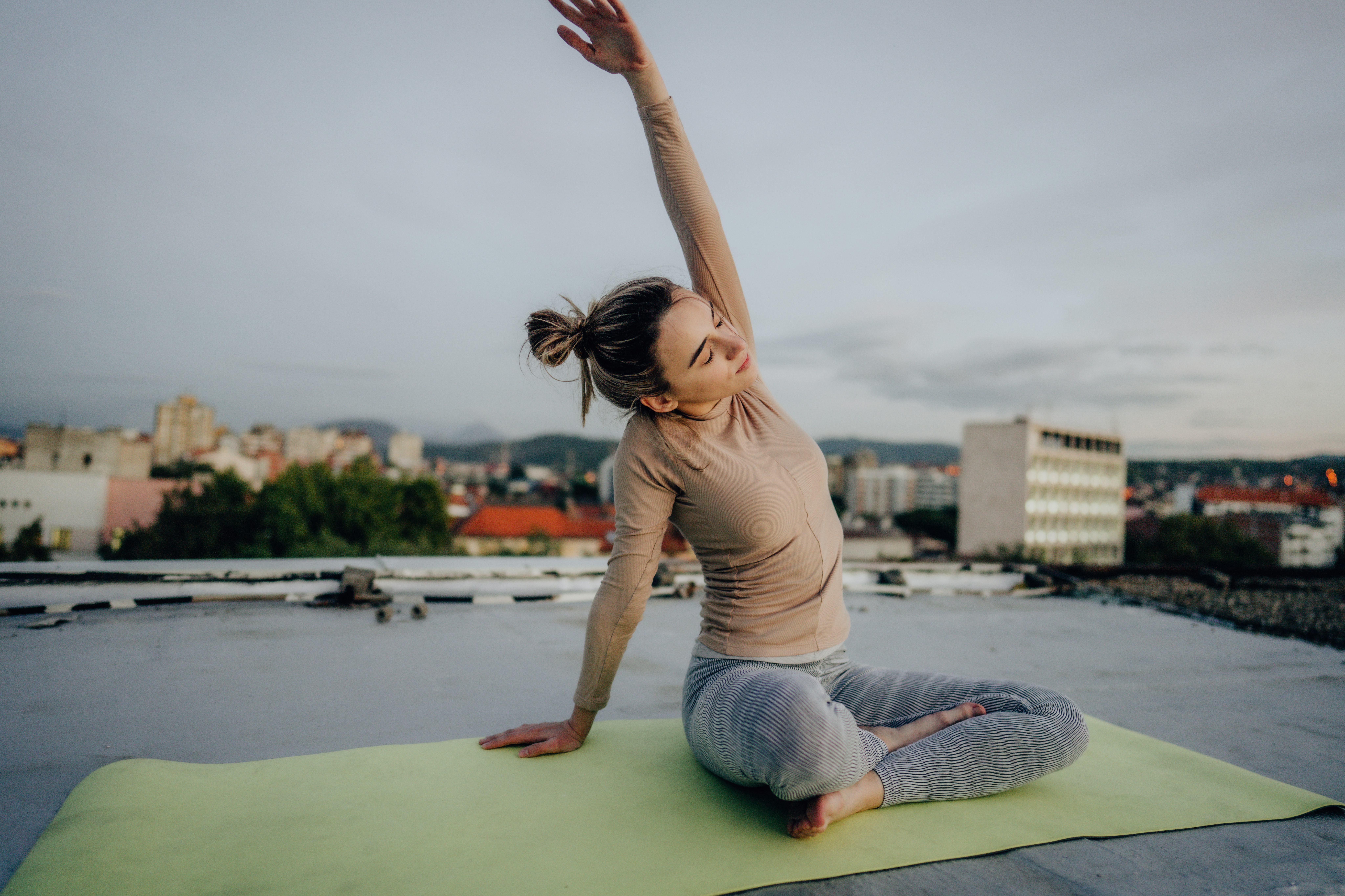 A woman does yoga on a roof. A ClassPass report reveals the most popular virtual workouts of 2020.