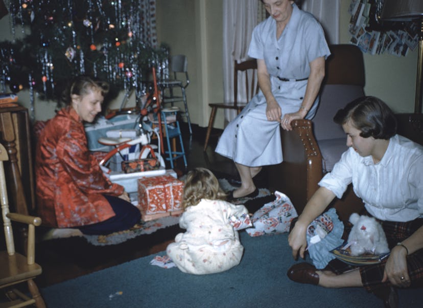 This vintage Christmas photo shows a family unwrapping gifts on Christmas morning.