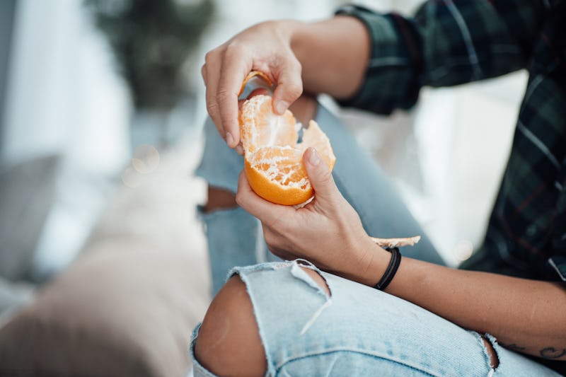 A person peels an orange.  Tiktokers are eating burnt oranges to get their taste back post-covid. A ...