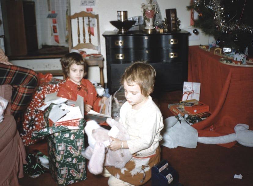 This vintage Christmas photo shows two children opening gifts. 