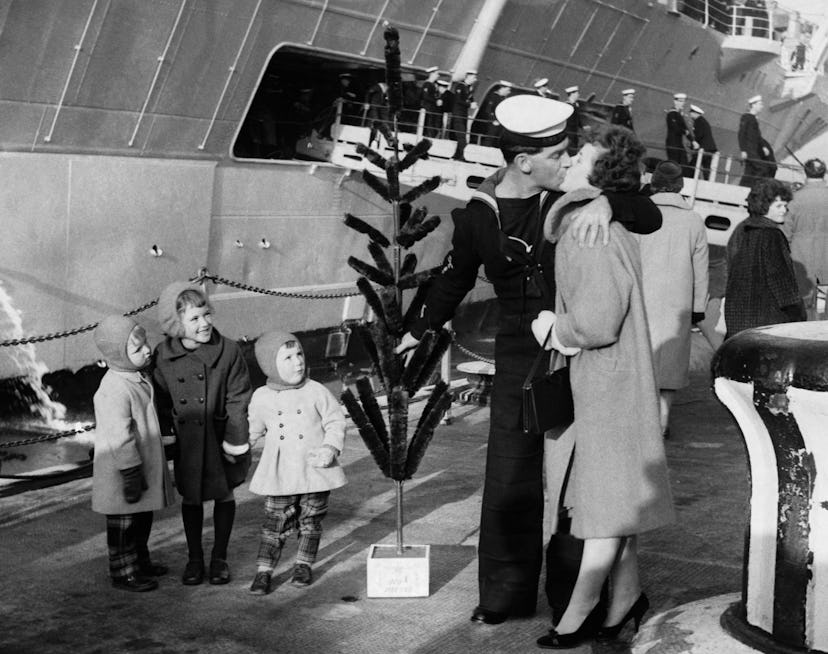 This vintage Christmas photo shows a family welcoming a sailor home for the holidays.
