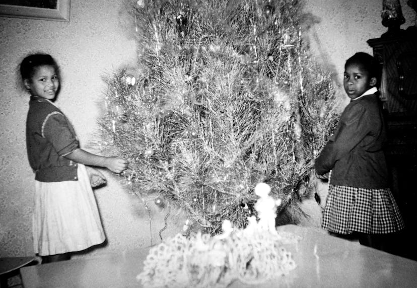 This vintage Christmas photo shows two girls decorating their tree. 