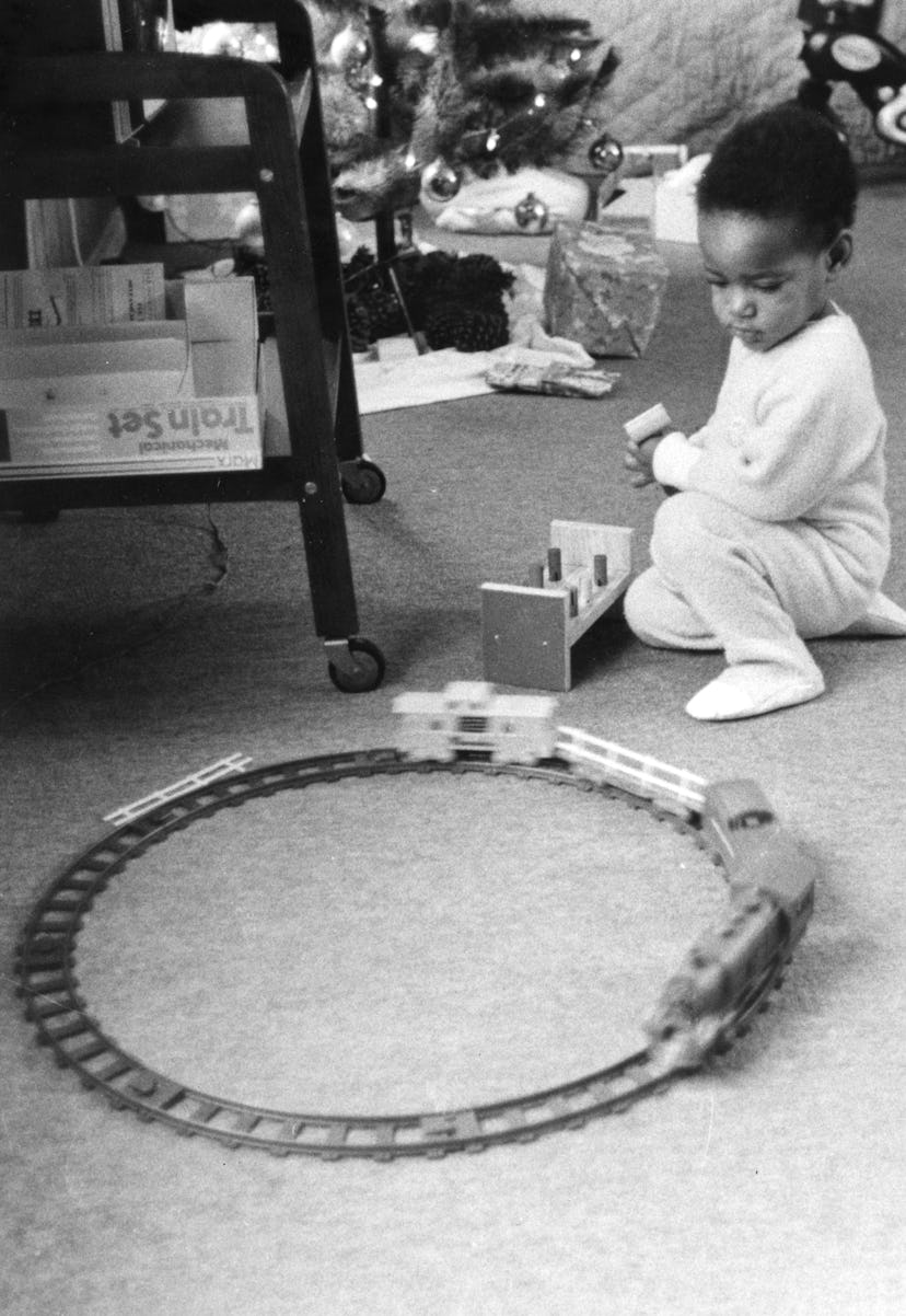 This vintage Christmas photo shows a little boy playing with a train set. 