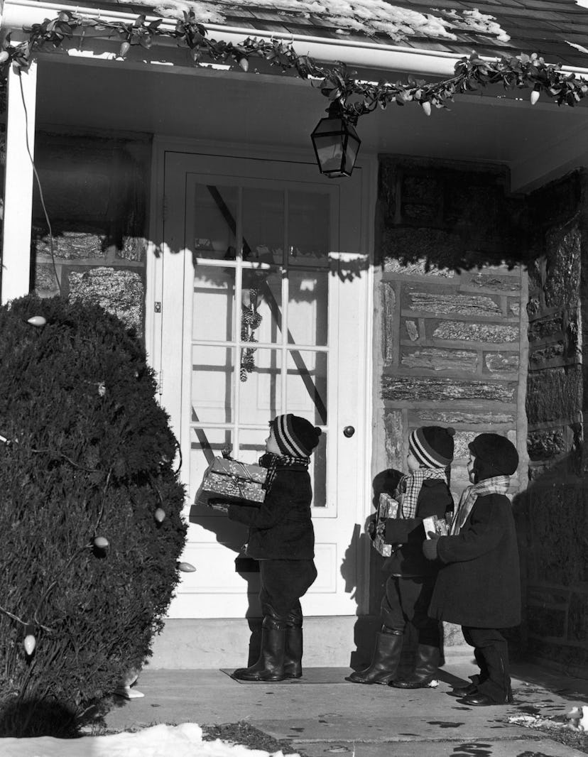 This vintage Christmas photo shows children delivering gifts to neighbors.