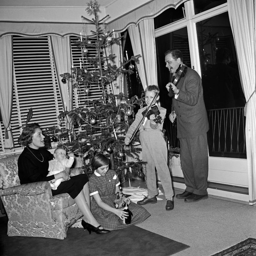 This vintage Christmas photo shows a family playing instruments around their tree.