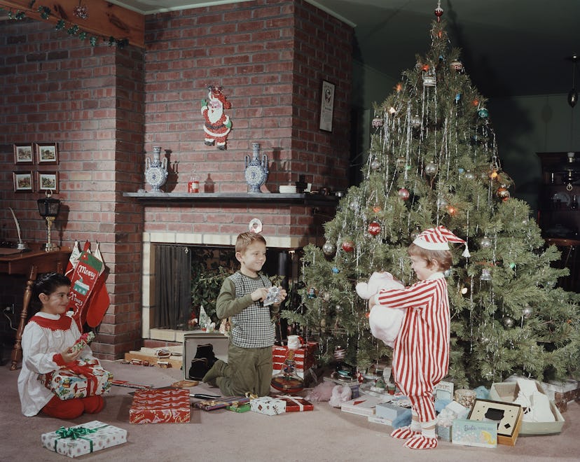 Children playing in front of the tree in this vintage Christmas photo is such a classic scene.