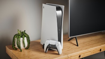 A white Playstation gaming console and joystick next to a TV on a wooden surface
