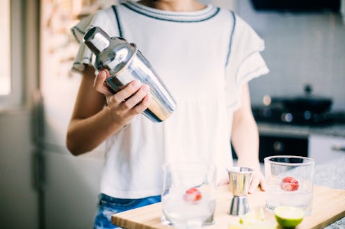 A woman mixes a cocktail. Does alcohol go bad? Yes, booze goes bad after a certain shelf life.