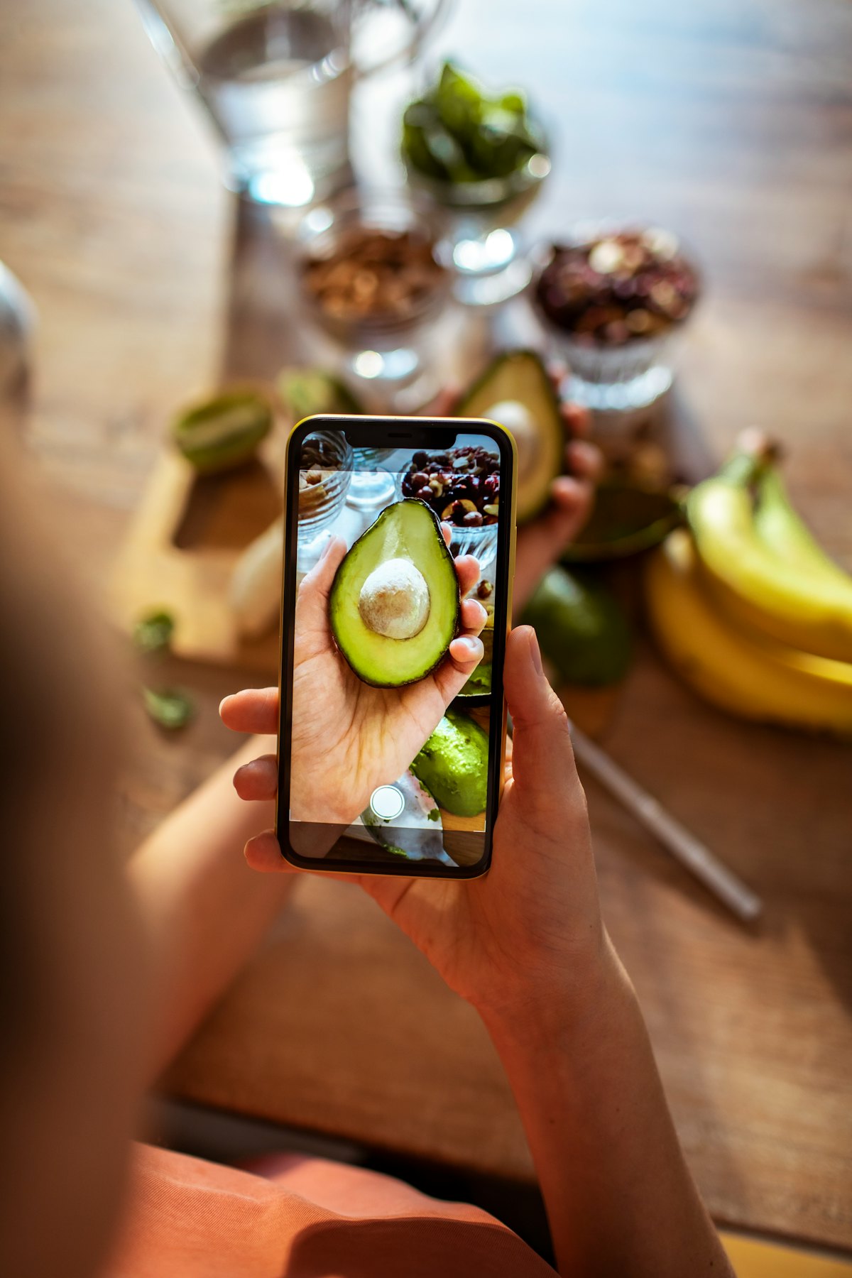 A woman takes a photo of an avocado.