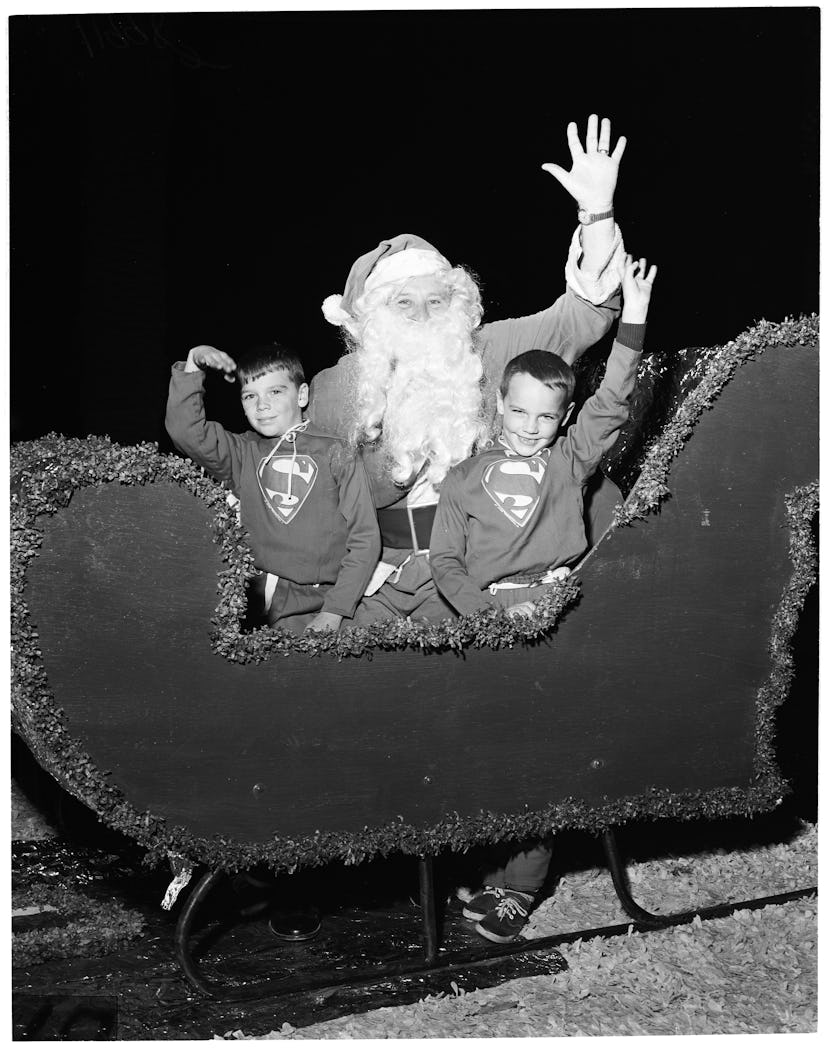 This vintage Christmas photo shows two boys riding in Santa's sleigh during a parade.