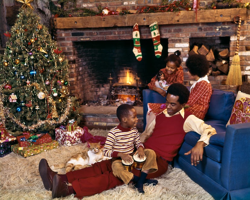 This vintage Christmas photo features a family relaxing in front of the fireplace.