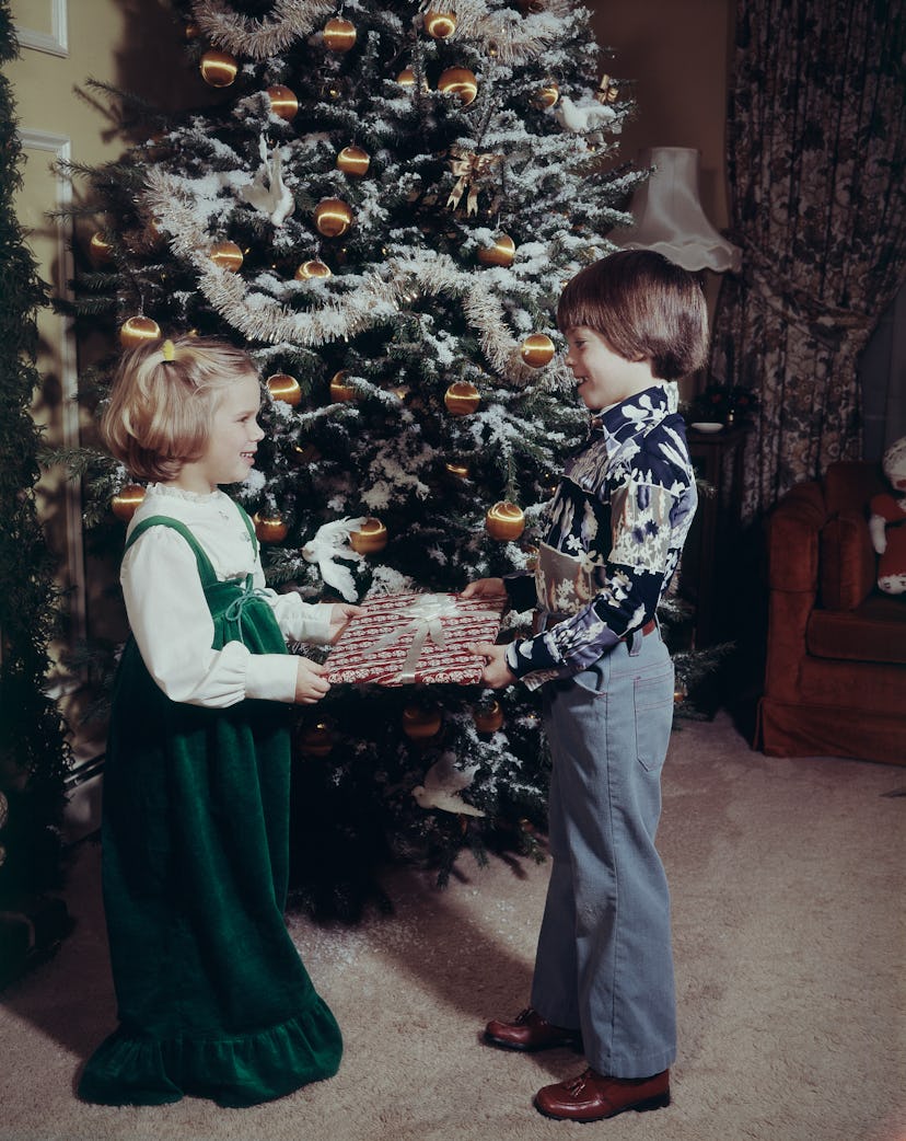 This vintage Christmas photo shows two children exchanging gifts.