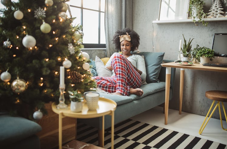 A cozy woman in her festive PJs lounges on the couch.