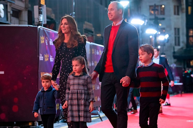 Prince William, Kate, and their children walk hand in hand on the red carpet. 