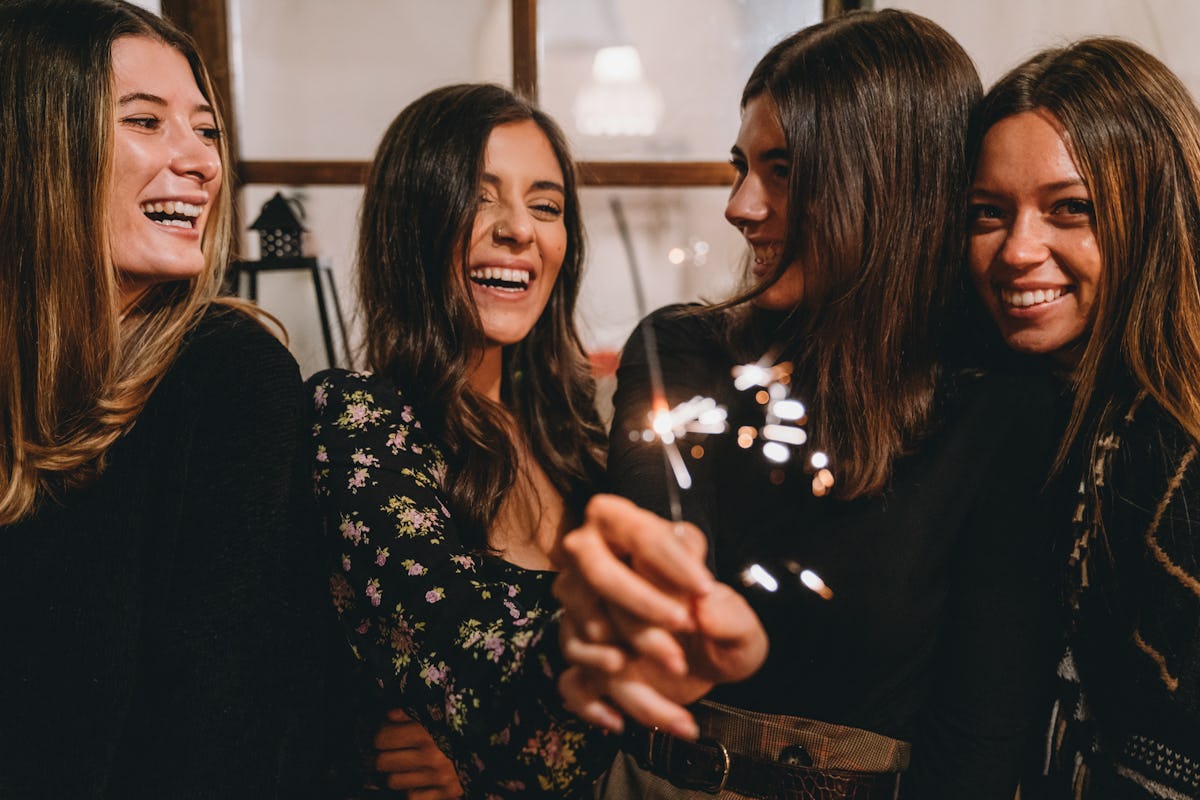 Four friends celebrate on New Year's Eve at home with sparklers.