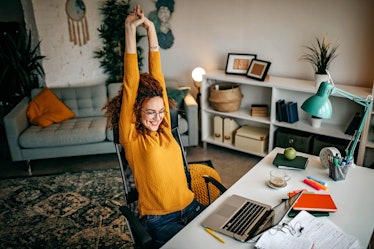 A cozy student stretches at her new WFH desk, full of gadgets and organizers to stay productive. 