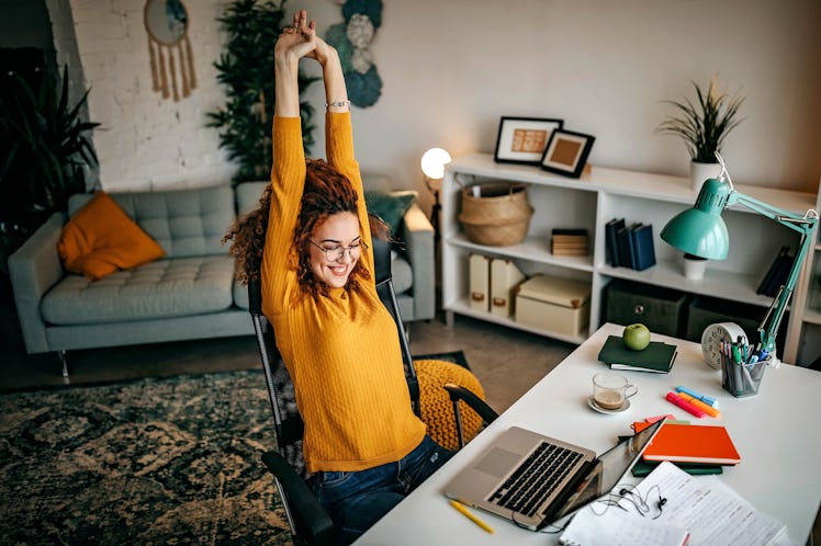A cozy student stretches at her new WFH desk, full of gadgets and organizers to stay productive.