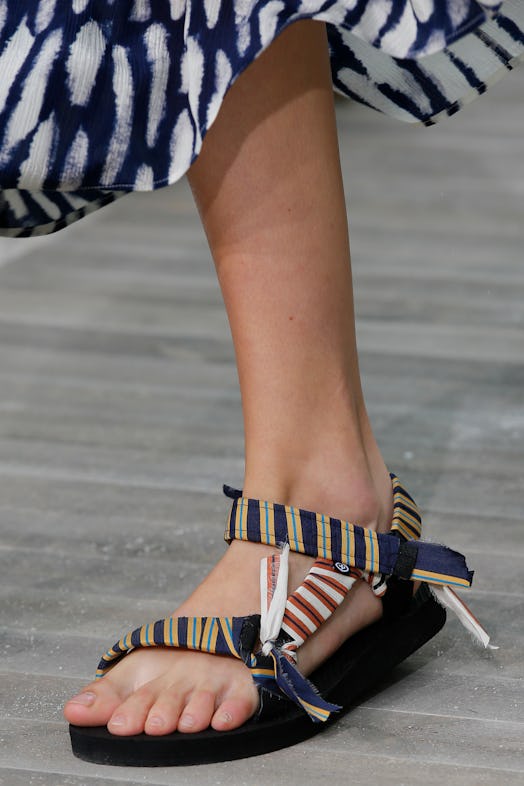A model's foot in a striped, fabric-covered sport sandal, a 2021 shoe trend making a comeback