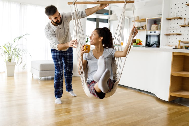 A young couple plays with a swing in their living room while wearing loungewear on New Year's Eve.