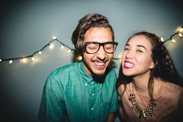 A happy couple celebrate the New Year at home with string lights. 