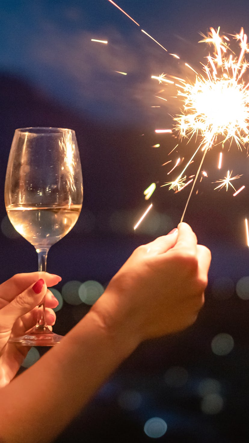close up of a hand with champagne and a sparkler