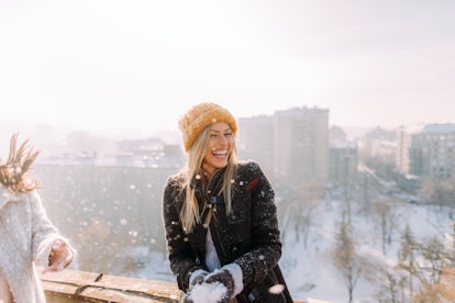A happy blonde woman laughs while getting ready to throw a snowflake on a sunny day.
