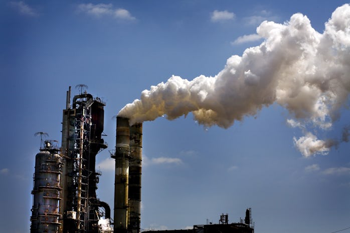 An Exxon factory with an industrial sized pipe billowing a gigantic cloud of smoke.