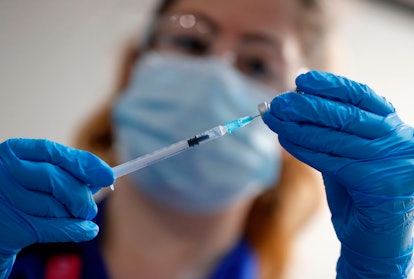 A healthcare provider handles a COVID-19 vaccine in a needle.
