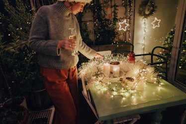 A woman looks down at her cozy candle table setup for Christmas.
