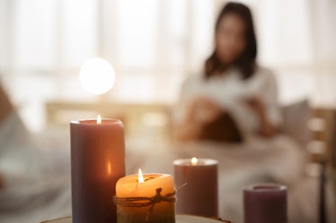 A woman relaxes in her home by her candles.