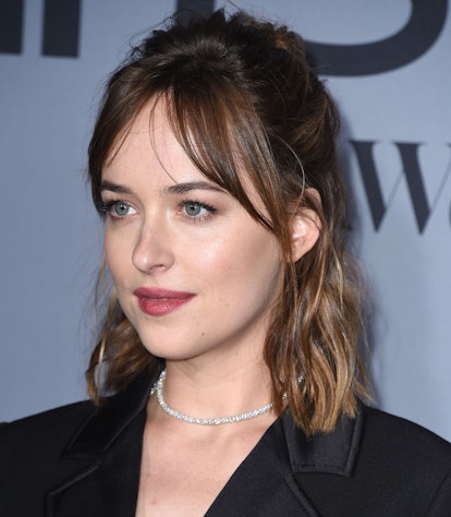 Dakota Johnson styles curtain bangs in a half-up, half-down style