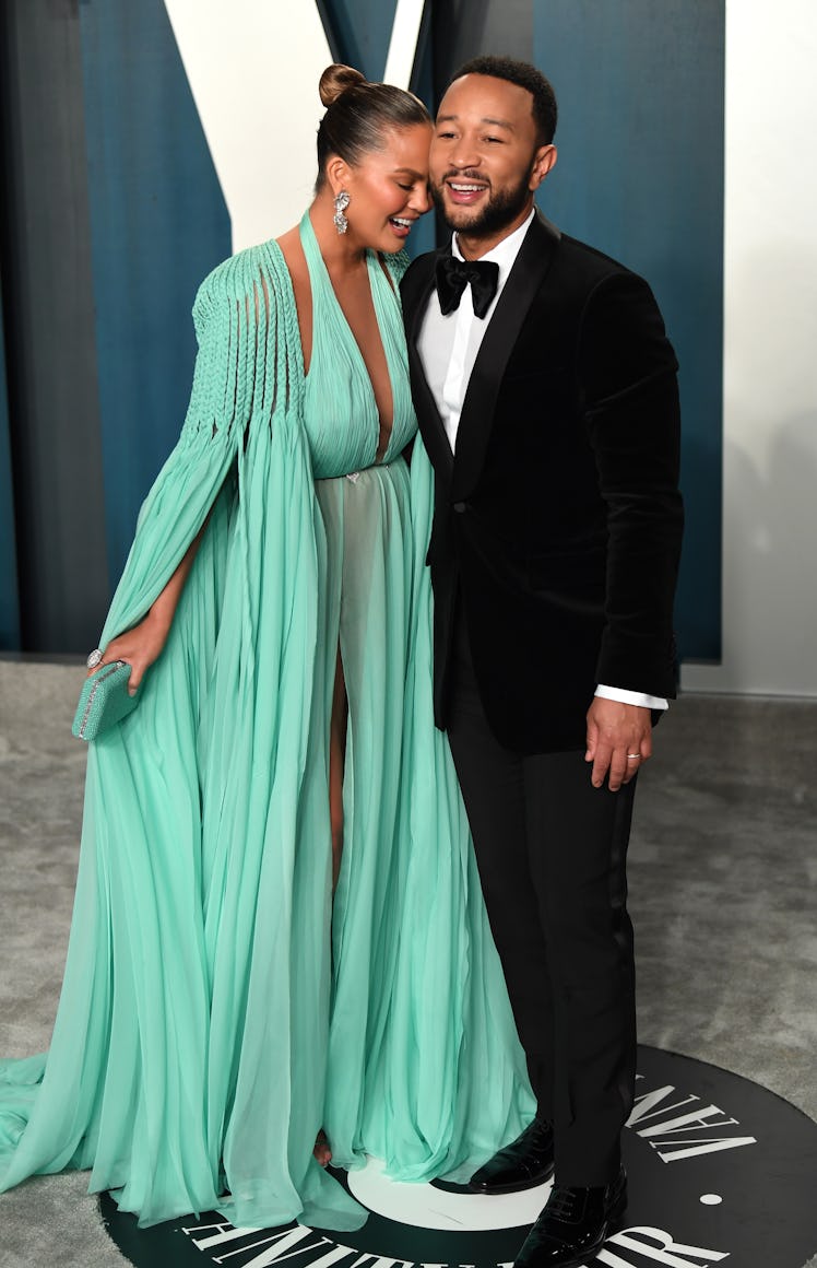 Chrissy leaning on John while they were posing on the carpet at Vanity Fair Oscar party