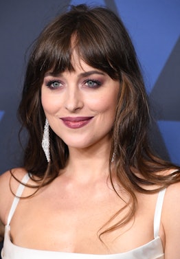  Dakota Johnson styles curtain bangs with volume and a slight middle part
