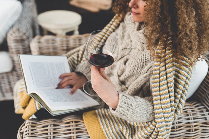 woman reading book and having a glass of wine