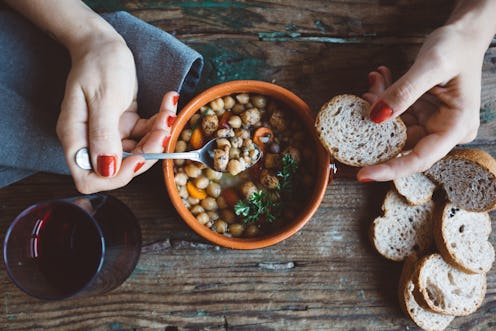 A woman eats a hearty vegan stew. What can going vegan do to your body?