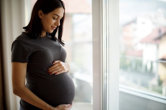 a pregnant woman standing in front of a window