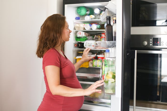 pregnant woman looking in fridge