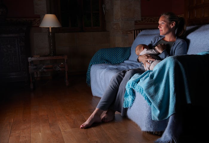 mom breastfeeding on a couch at night