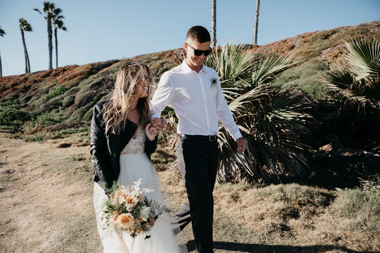 A young couple laughs in wedding attire after getting married in the desert.