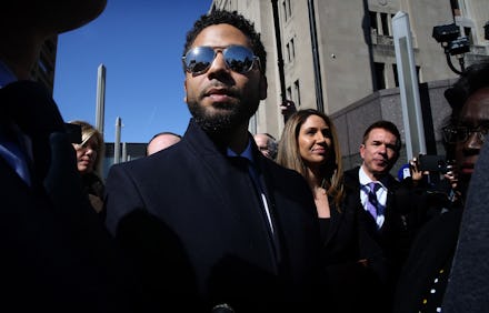 Jussie Smollett wearing a suit and sunglasses, accompanied by his legal team