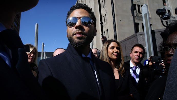 Jussie Smollett wearing a suit and sunglasses, accompanied by his legal team