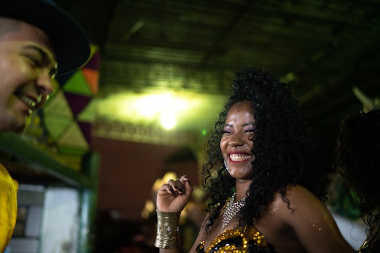 A woman smiles and dances in her Mardi Gras outfit.