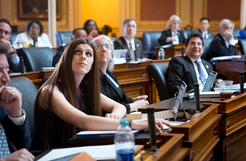 Danica Roem surrounded by a large group of men in a conference room