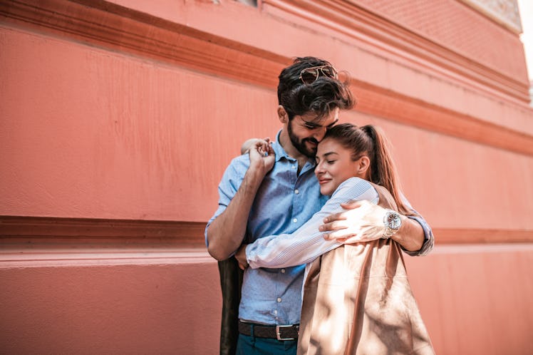 A happy couple embraces while exploring a city.
