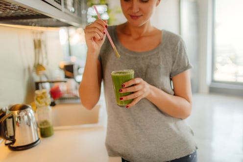 A woman fixes herself a green smoothie in her kitchen. Intuitive eating is touted as a way to fix re...