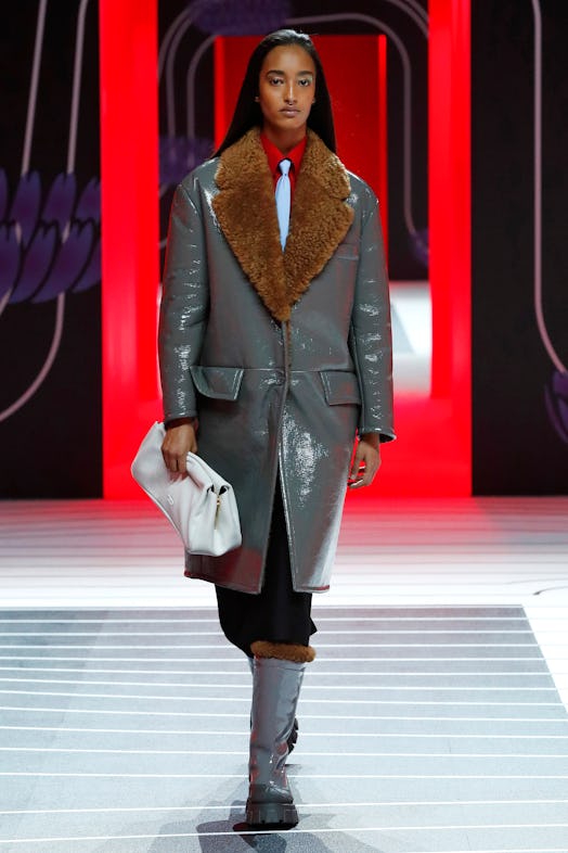 A model walking the Prada Fall 2020 runway in a grey leather coat with a fur collar 