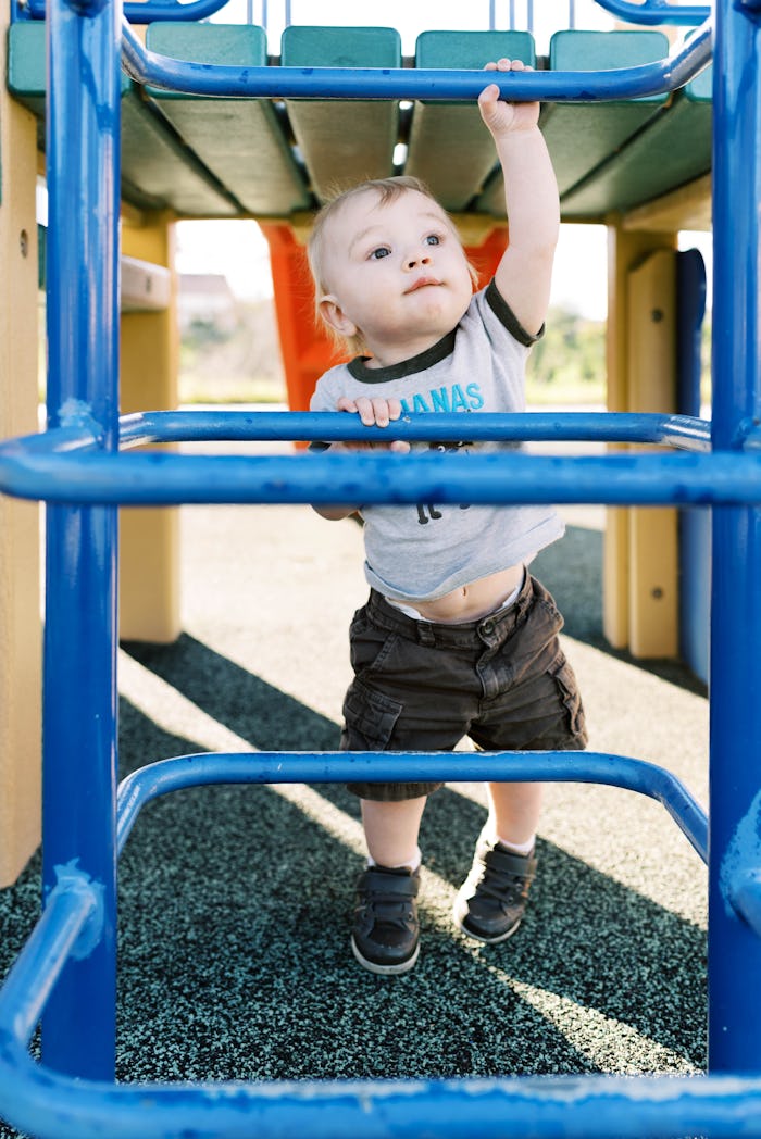 a toddler boy climbing up a jungle gym