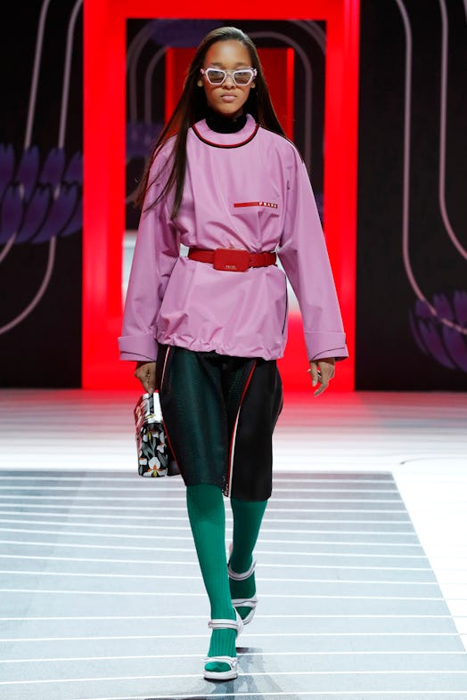 A model walking the Prada Fall 2020 runway in a belted pink crewneck sweatshirt