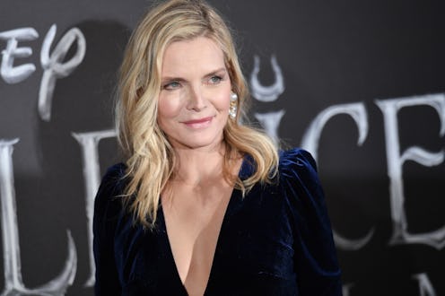 Michelle Pfeiffer in a deep V-neck navy dress and large white earrings on a red carpet event